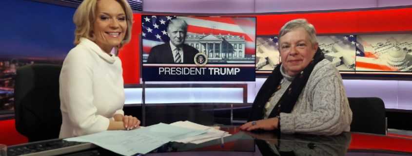 Screenshot of US news desk with President Trump on the background screen
