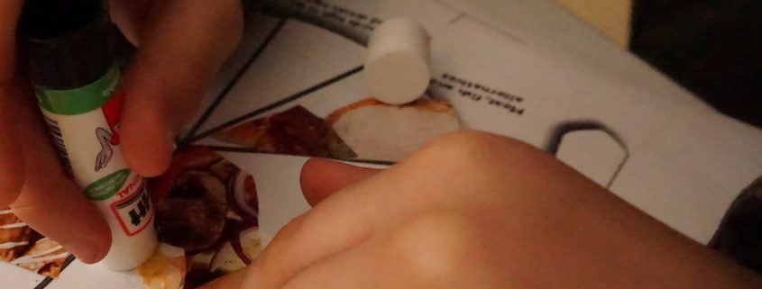child gluing pictures onto food plate sheet
