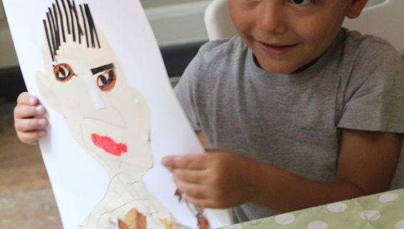 A young boy holds up a collage self-portrait